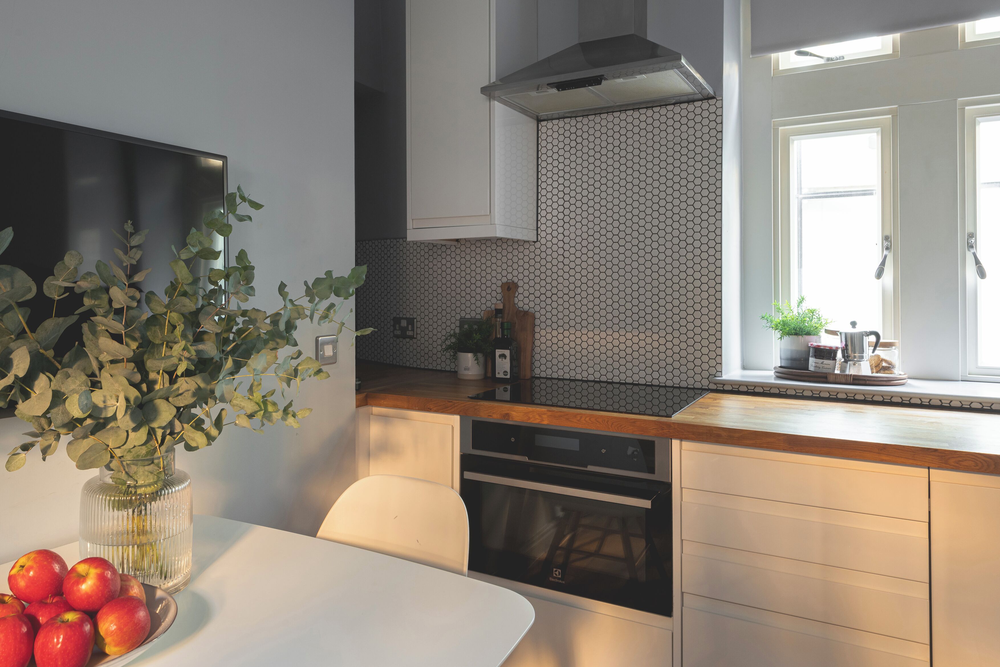 Una cucina moderna con un piano di lavoro bianco, un forno integrato e una finestra con vista.