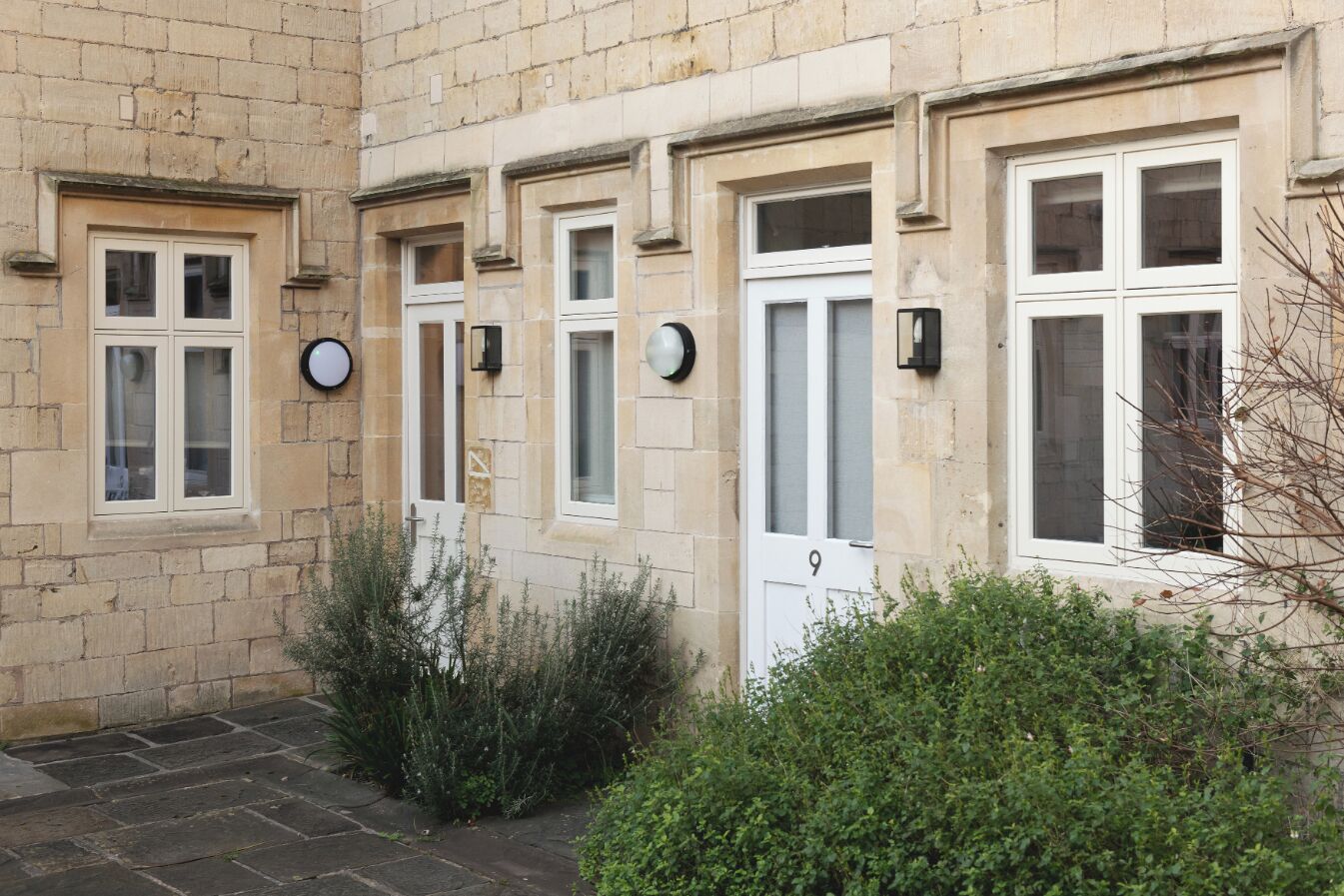 A stone building with multiple windows and doors, some with glass panes.