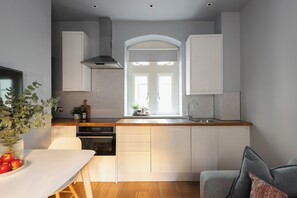 A modern kitchen with white cabinets, a wooden countertop, and a built-in oven. - St Catherine's Hospital - Bath (Bath)
