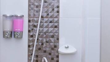 Ducha con cabezal de ducha manual, grifo empotrado y dispensador de jabón.
