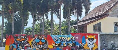 A mural with a tiger and a cartoon character, outdoor seating, and palm trees.