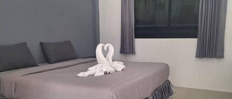Een moderne slaapkamer met een groot bed, grijze wanden en een raam met gordijnen.