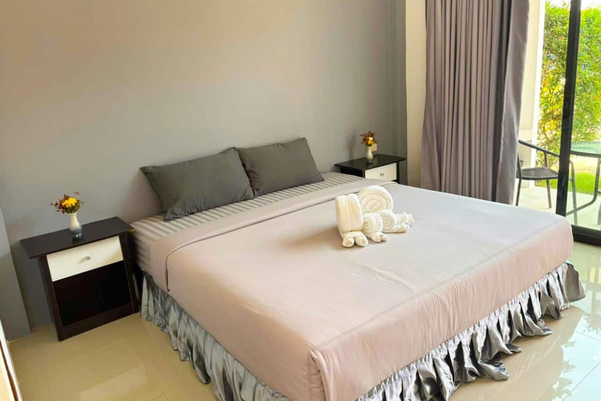 A modern bedroom with a large bed, two bedside tables, and a view of the outdoors.