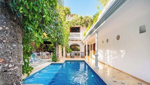 A swimming pool with a stone wall on one side and a white building on the other. - Casa Palos - 5 BR Downtown Luxury House (Cartagena de Indias)