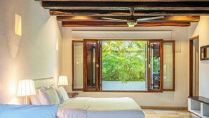 A bedroom with a bed, two bedside lamps, a ceiling fan, and a window with open shutters. - Casa Palos - 5 BR Downtown Luxury House (Cartagena de Indias)