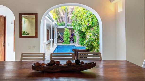 A dining area with a view of a pool and garden. - Casa Palos - 5 BR Downtown Luxury House (Cartagena de Indias)