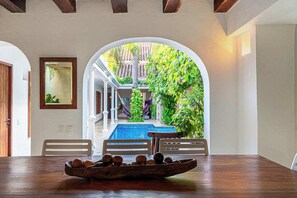 A dining area with a view of a pool and garden.