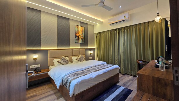 Une chambre d’hôtel moderne, dotée d’un grand lit, d’un bureau et d’un ventilateur de plafond.