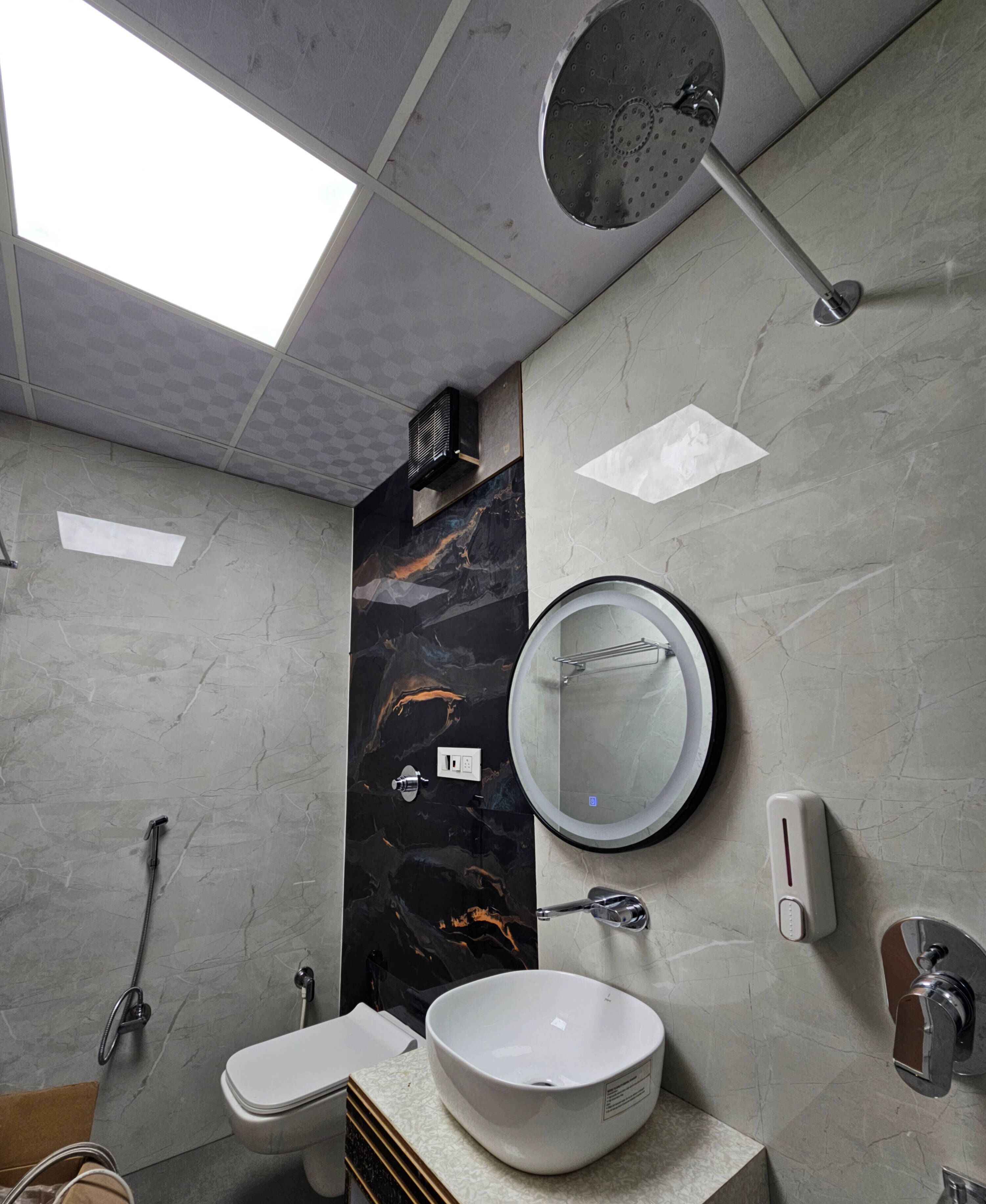 A modern bathroom with a skylight, a round mirror, a white sink, and a handheld showerhead.