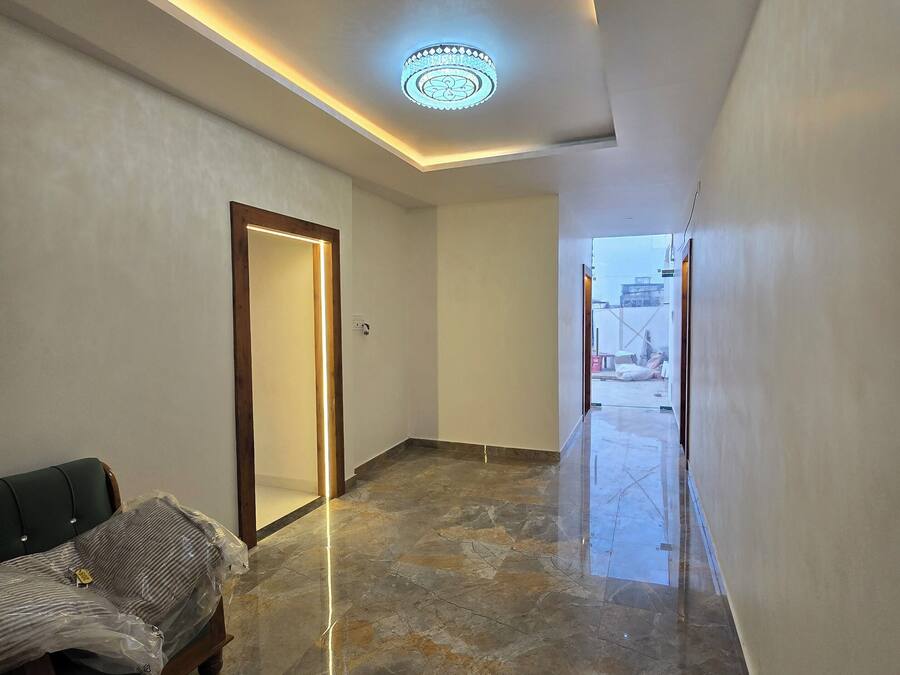 Un pasillo moderno con suelo de mármol, una puerta de madera y un sofá cubierto de plástico.
