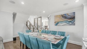 A dining area with a large table set for six, light blue upholstered chairs, and a modern abstract painting on the wall. - Spacious 5-bedroom house in lovely Arlington with AC, WiFi (Arlington)