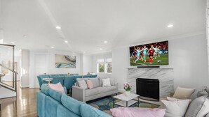 A modern living room with a large TV, a fireplace, and a seating area with sofas and a coffee table. - Spacious 5-bedroom house in lovely Arlington with AC, WiFi (Arlington)