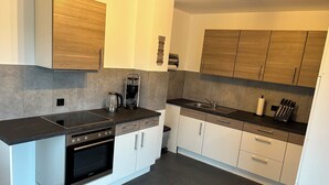 A modern kitchen with a built-in oven, a coffee maker, and a sink. - Hus Heideblick between nature and the North Sea (Sankt Michaelisdonn)
