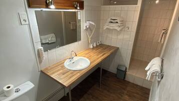 Un bagno con un mobiletto in legno, un lavandino bianco, uno specchio, un water e una zona doccia.