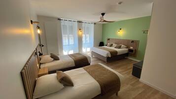 Habitación de hotel con dos camas, ventilador de techo y ventana con cortinas.