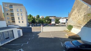 A parking lot with multiple cars, a building with a flat roof, and a clear blue sky. - NOUVEL HOTEL  (Lons-le-Saunier)