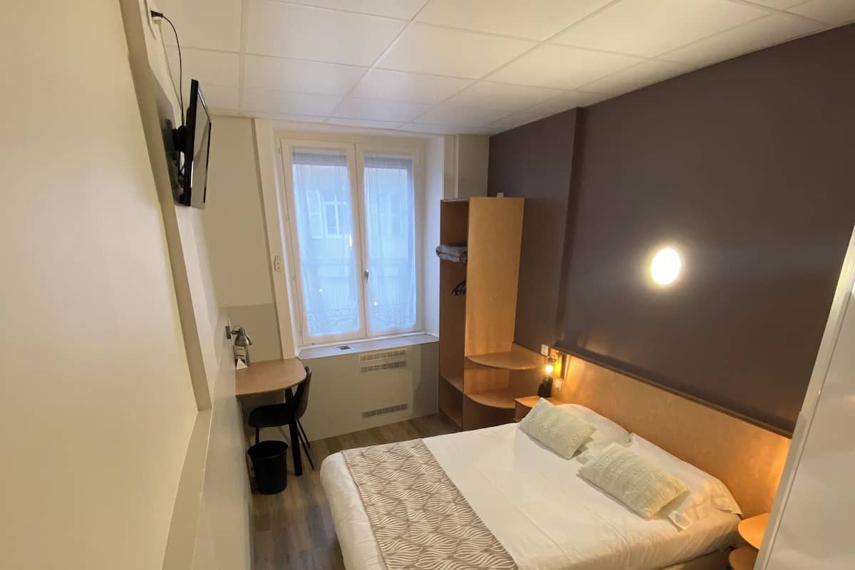 Une chambre à coucher comprenant un lit, un bureau, une chaise, une fenêtre et une armoire.