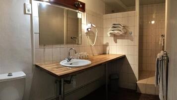 Ein Badezimmer mit einem Holzbadezimmermöbel, einem Waschbecken, einem Spiegel, einer Dusche und einem Handtuchhalter.