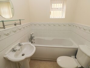 A bathroom with a bathtub, toilet, and sink. - 21 Heol Gylfinir (Barry)