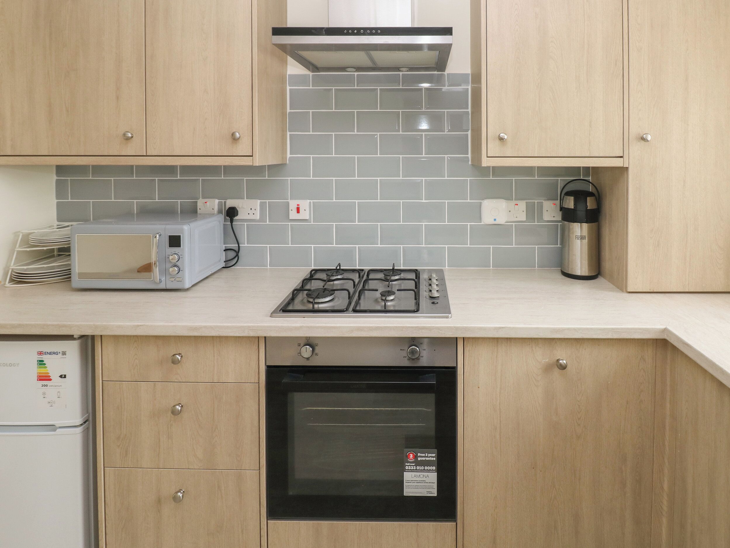 A kitchen with a gas stove, microwave, oven, and a coffee maker.