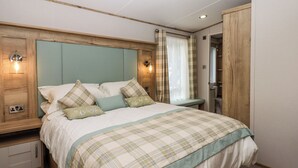A bedroom with a bed, bedside tables, a wardrobe, and two wall-mounted lights. - Ambleside (Cullompton)
