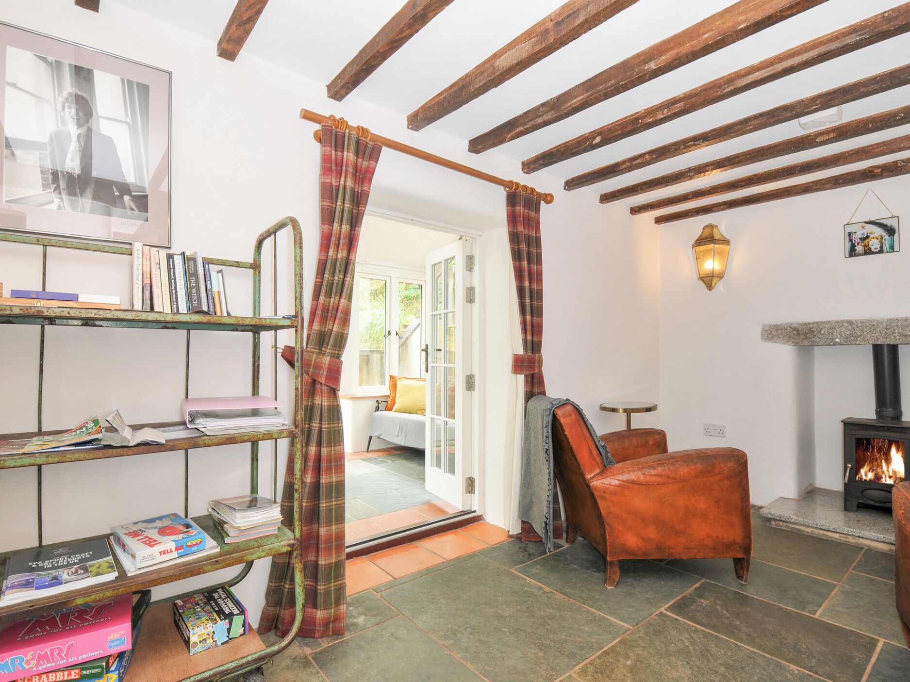 A cozy room with a fireplace, a bookshelf, and a plaid curtain.