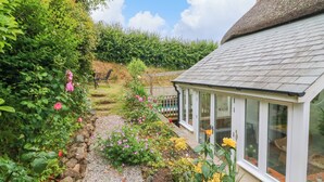 A garden path leading to a house with a thatched roof and large windows. - Rose Cottage (Okehampton)