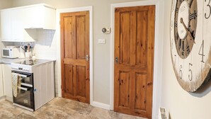 A kitchen with wooden doors, a microwave, and a stove. - The Crib (Llandudno)