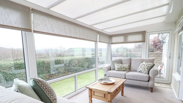 A spacious room with a large window, a sofa, a wooden coffee table, and a view of the outdoors. - The Crib (Llandudno)