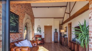 A spacious living area with a leather sofa, a wooden coffee table, and a brick wall. - Molly's Cottage (Malton)