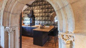 A kitchen with a stone backsplash, a central island, and a hanging light fixture. - Molly's Cottage (Malton)