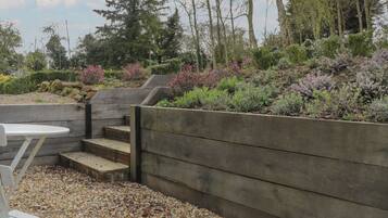 Un jardin avec un banc en bois, une table et un mur en pierre.