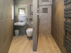 A modern bathroom with a toilet, sink, and shower. - Y Bwthyn (Dolgellau)