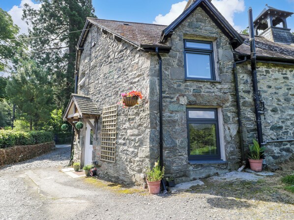A stone building with a sloped roof, a small porch, and a window. - Y Bwthyn (Dolgellau)