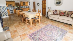 Ein geräumiger Wohnbereich mit Esstisch, Sofa und einer Küche im Hintergrund.
