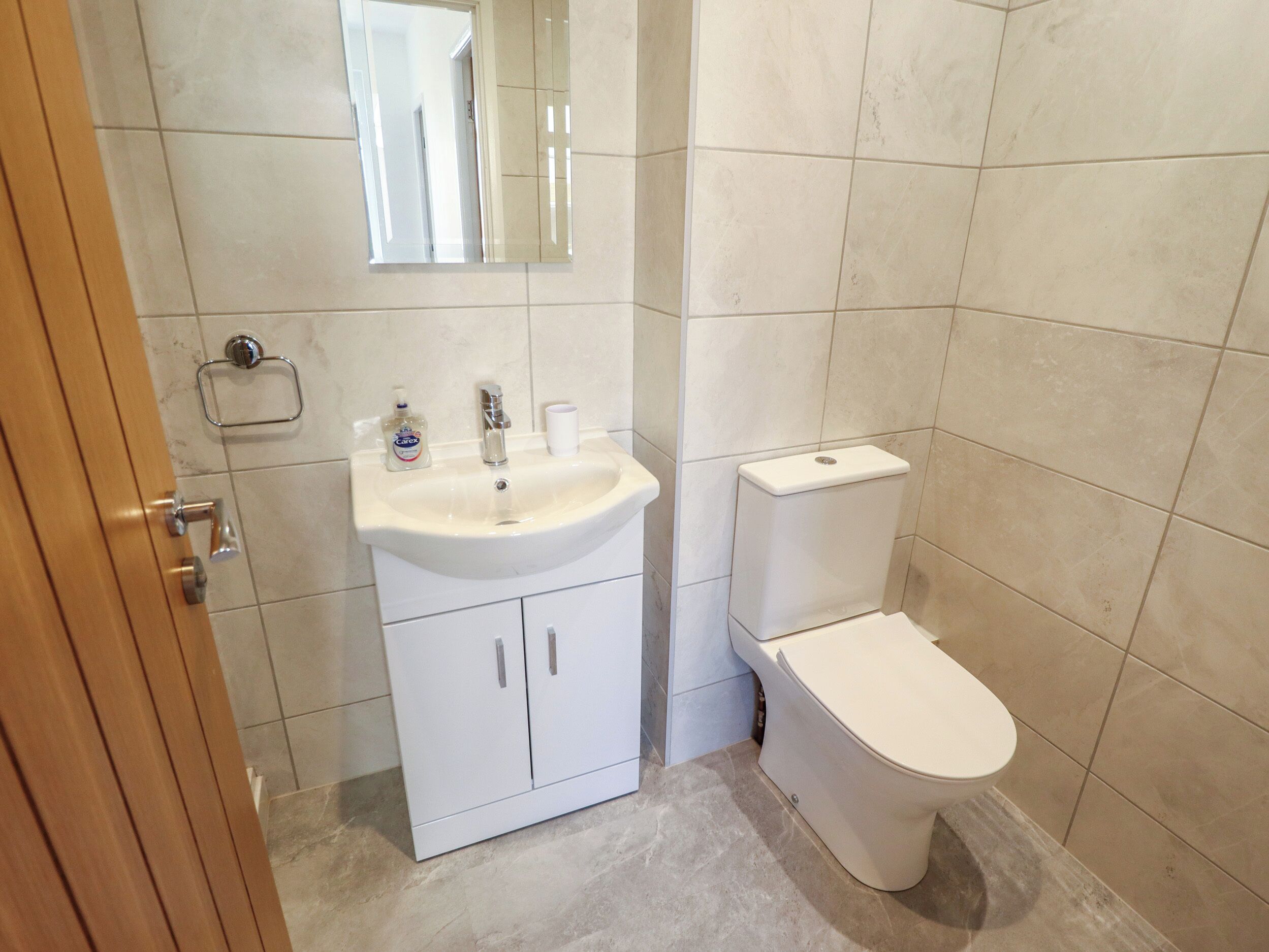 A bathroom with a white sink, mirror, and toilet.