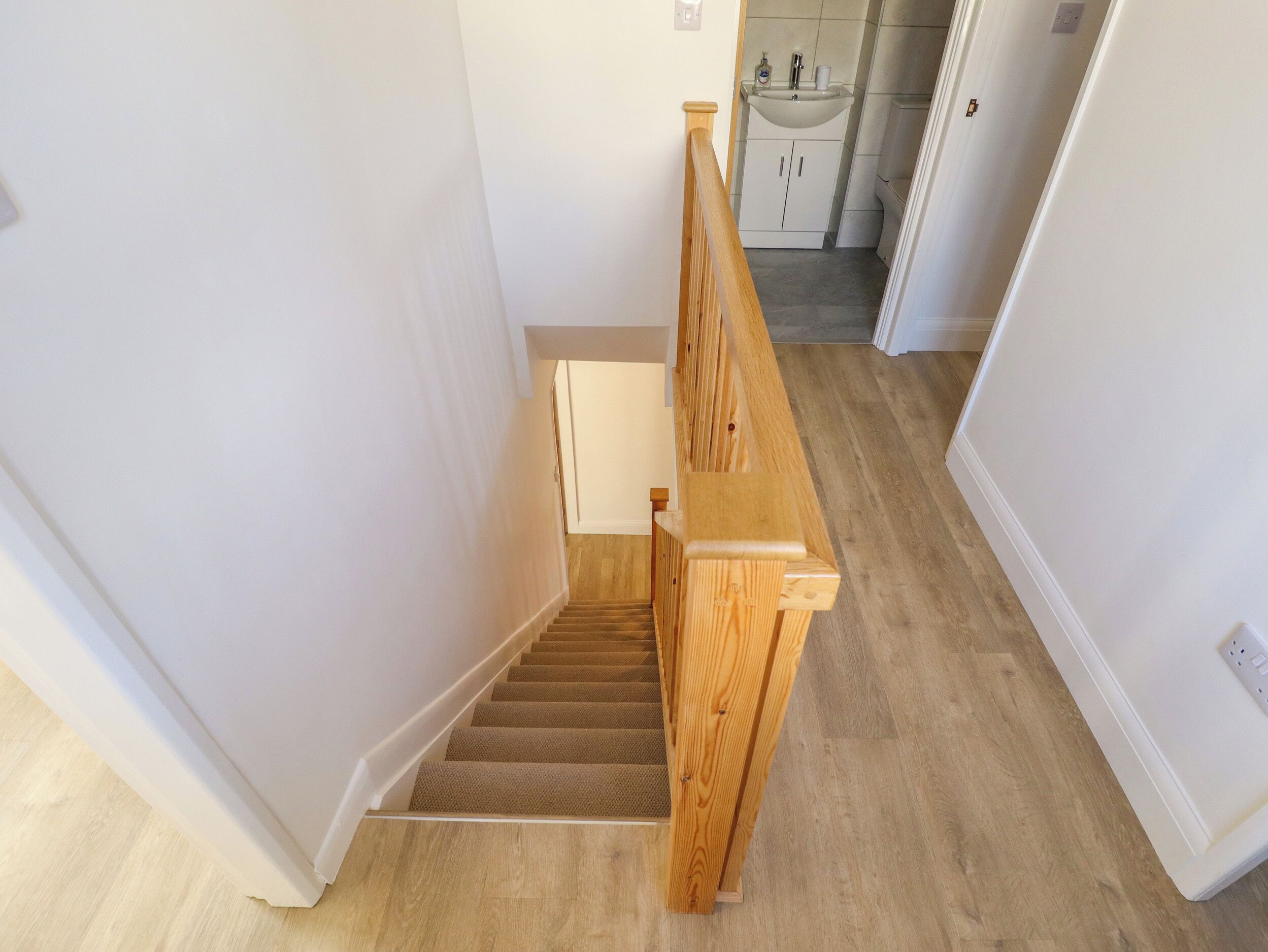 A wooden staircase with a handrail leading to a landing.