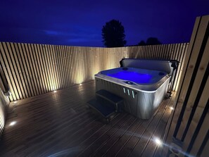 A hot tub on a wooden deck at night. - Beach Haven (Skegness)