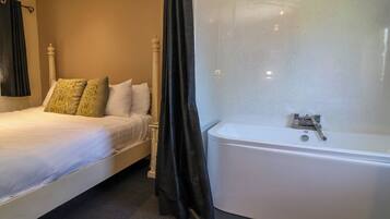Um quarto com cama, banheiro com banheira e cortina de chuveiro.