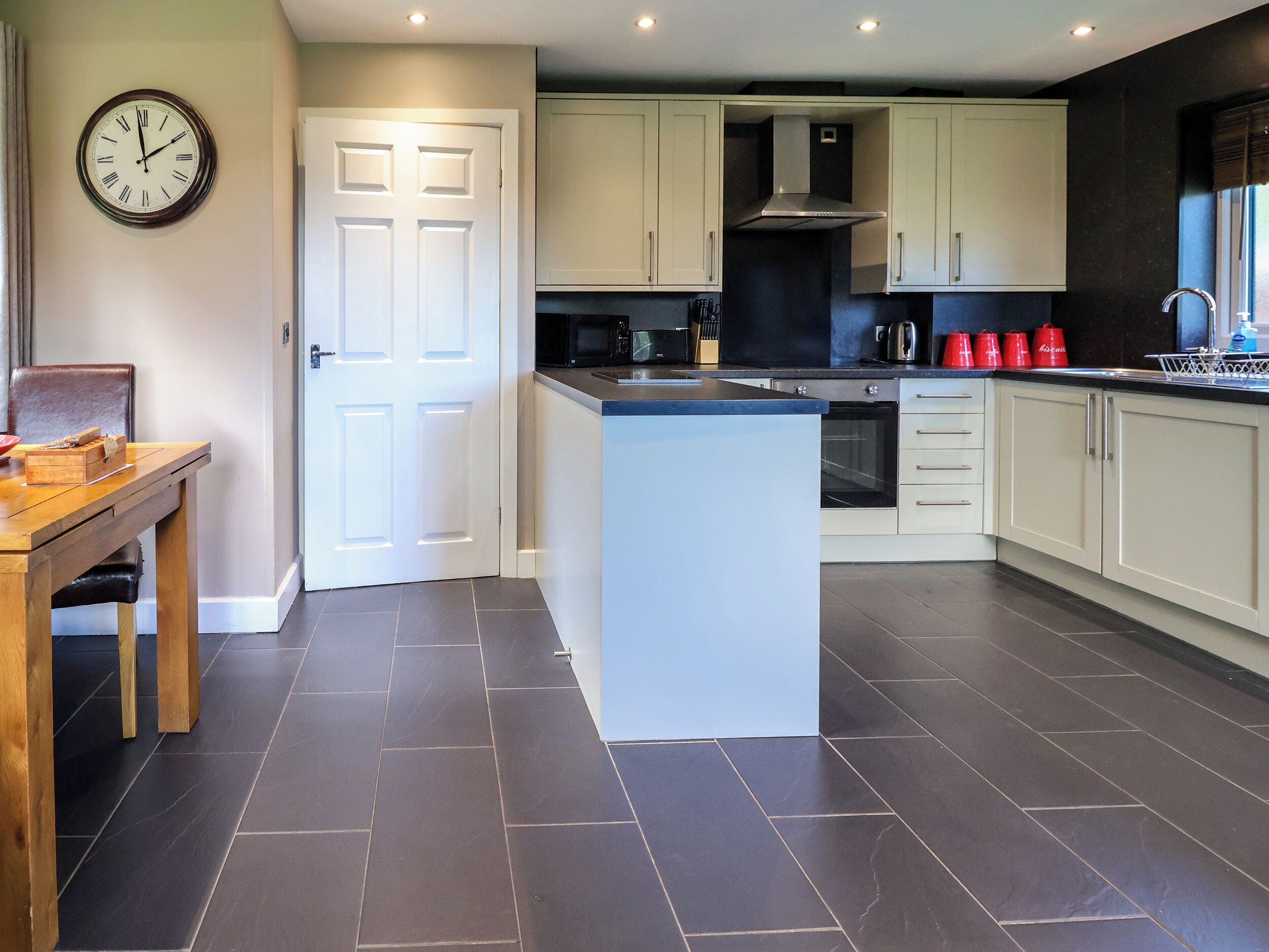 A modern kitchen with white cabinets, a central island, and a dining area with a wooden table.
