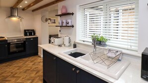 A modern kitchen with a built-in oven, a toaster, a kettle, and a sink with a window above.