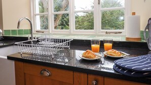 A kitchen with a window, a sink, and a dish rack. - Culver Court Cottage (Crediton)