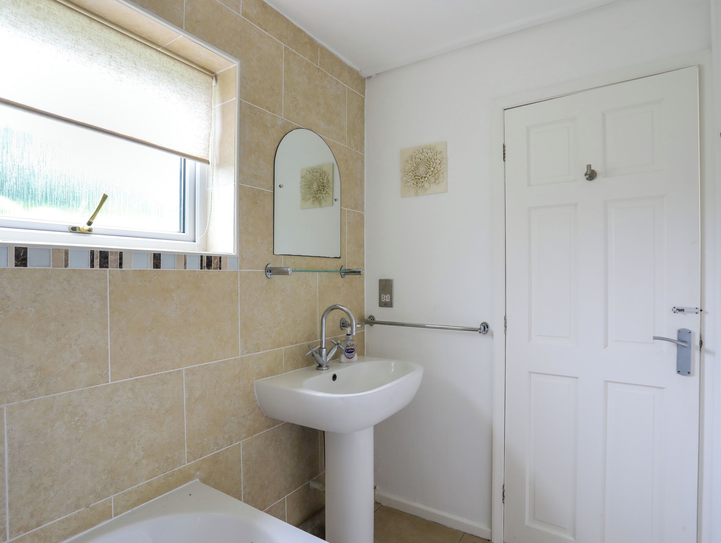 Une salle de bain avec une baignoire, un lavabo, une fenêtre et une porte.