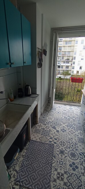 Compact kitchen with a sink, teal cabinets, and a window offering a view of the surrounding area.