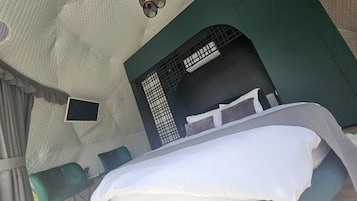 A tent-style room with a bed, a small table, and a chair.