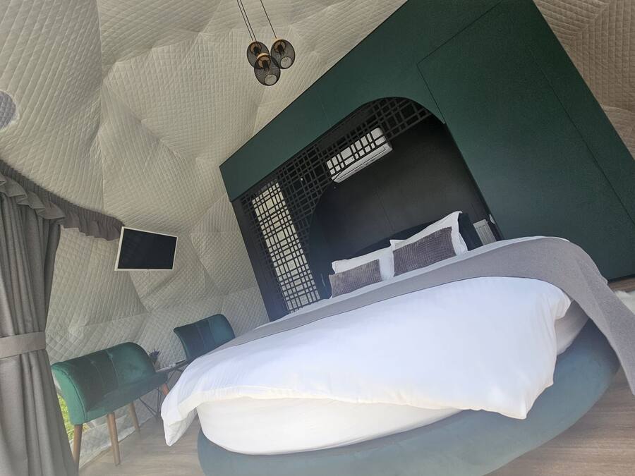 A tent-style room with a bed, a small table, and a chair.