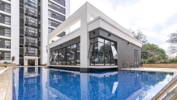 En moderne bygning med swimmingpool, store vinduer og en terrasse.
