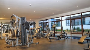 Et fitnesscenter med forskellige træningsmaskiner, en pool og store vinduer med udsigt ud