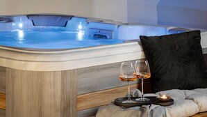 Un jacuzzi con dos copas de vino y una vela sobre una bandeja.