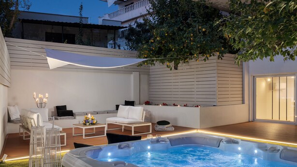 Un área moderna de hidromasaje al aire libre con asientos y una pérgola.